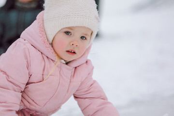 Little girl in pink walks outdoors on winter snowy day. High quality photo