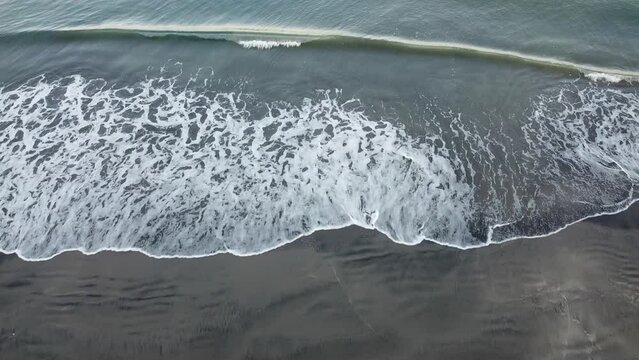 Drone shot of waves in the seashore with woman walking