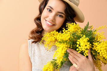 Beautiful young woman with mimosa flowers on color background