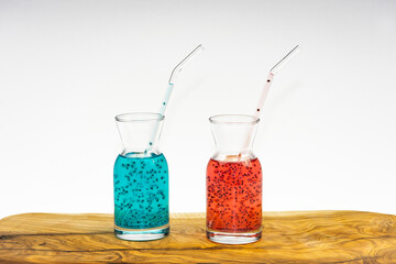 Watermelon and blueberry juices with basil seeds in glass cup with straw on wooden table and white background
