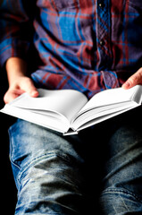 A man sits with a mock-up of a white book in his hands