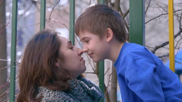 Son and mom kissing. Mother kiss her son outdoor