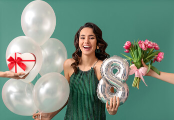 Smiling young woman with balloons receiving gifts on green background. International Women's Day