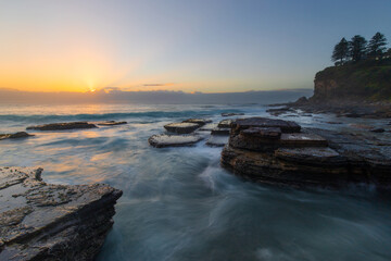 Fototapeta na wymiar Water flowing between big rocks on the coastline.