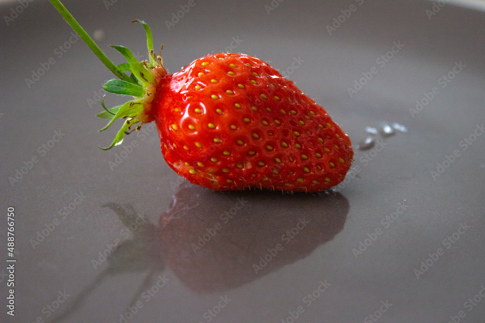 Poster Closeup shot of a strawberry on a dark gray plate