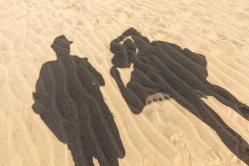 Schatten von Touristen mit Sonnenhut auf dem Sand