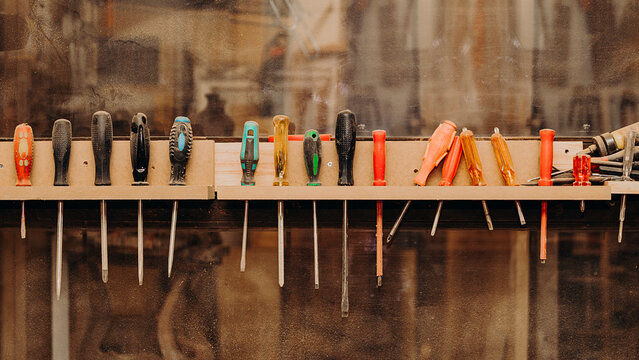 row of screwdrivers fastened on dusty shelf