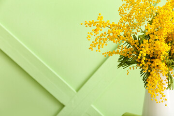 Vase with beautiful mimosa branches on color background, closeup