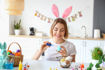 Beautiful woman painting Easter eggs at home