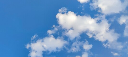 White fluffy cumulus clouds in the sky. Against the background of a dark blue sky, white and...
