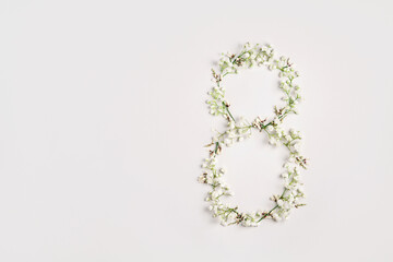 International women's day greeting card. White gypsophila flowers in shape of number eight on light grey background. 8 March concept. Festive spring holiday mockup. Top view, flat lay, copy space.
