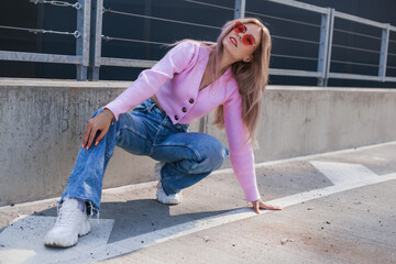 city walk in a modern form. Beautiful girl in a pink sweater and jeans and pink glasses. Modern style, positive attitude, urban look