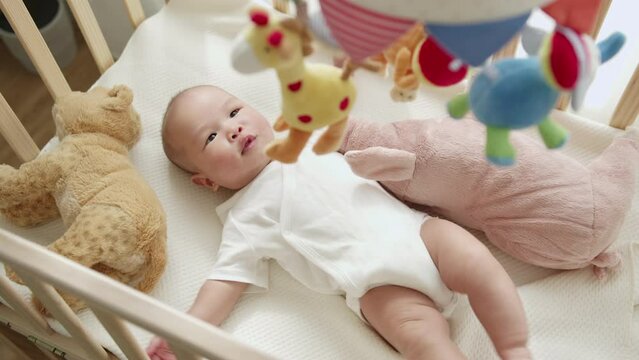 Asian newborn baby feeling joyful and happy with baby mobile crib