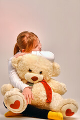 Girl hugging a toy bear. The child plays with a toy at home. Strong friendship .