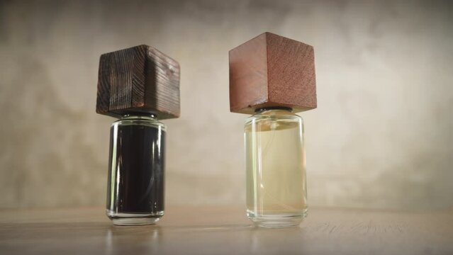 Two hands with rings and manicures put brutal perfume bottles in the frame. Bottles in the grunge style on a concrete postmodern background. Stylish perfumes in a gray interior. Testing of flavors.