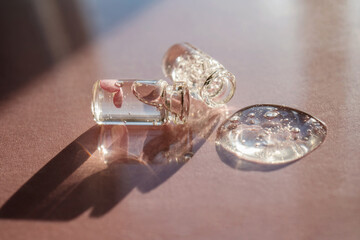 Two bottles of cosmetic gel on a pink background.