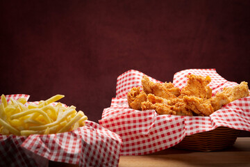 Fried chicken with fresh fries on the side in a studio shot