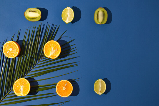 Summer tropical layout made with fresh fruit and palm leaves on blue background. Minimal natural flat lay. © miki1404