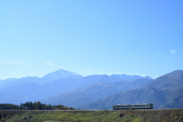 甲斐駒ヶ岳を背景に築堤を走る小海線ローカル列車