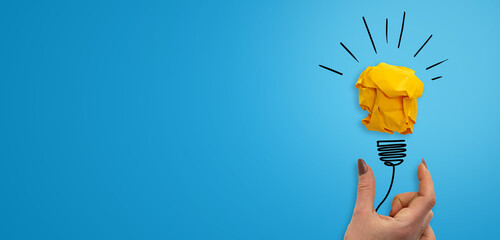 Banner blu con stazione copy, concetto di idea rappresentato da una lampadina di carta gialla con mano femminile.