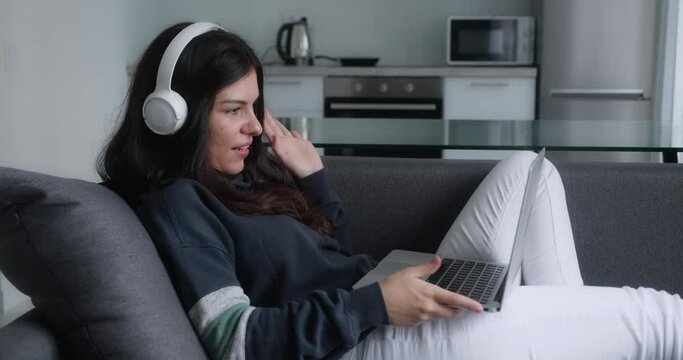 brunette woman have video calling for remote job interview using laptop webcam conference work lying in couch at home office. Happy lady talking by virtual chat meeting dating online using computer