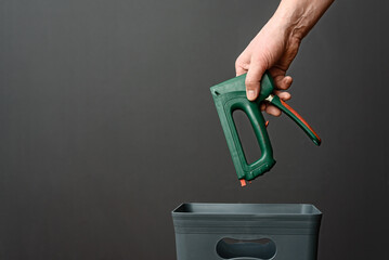 The construction stapler is thrown out of the trash for disposal