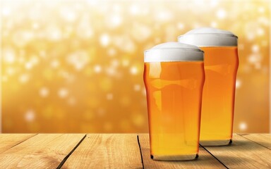 Glass mugs of cold beer with foam served on wooden table at night