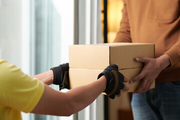 Close-up of man getting the parcel in box from delivery person
