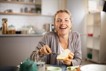Beautiful woman enjoying in breakfast. Happy young woman eating sandwich at home.
