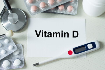 Medicine and health concept. VITAMIN D text on a card on a table next to a thermometer, tablets and stethoscope