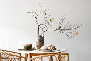 Served dining table with tree branches and Easter eggs in vase