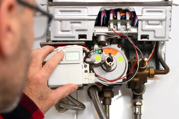 technician worker repairing water heater of butane or gas  without outer box being with low flame ,...