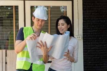 Asian professional architect holding blueprint and explain about the plan with homeowner for house...