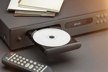 Fototapeta premium CD player, open disc tray, remote control on the table. Close-up, studio shot.