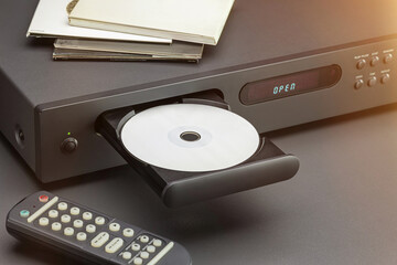 CD player, open disc tray, remote control on the table. Close-up, studio shot.