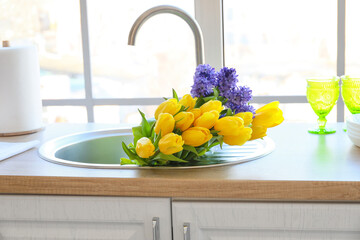 Bouquet of beautiful flowers in modern sink near window
