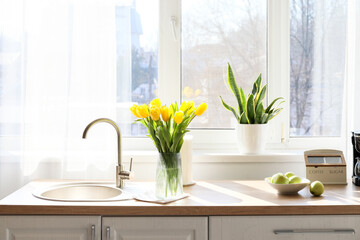 Kitchen counter with modern sink, beautiful tulips and fresh apples near window