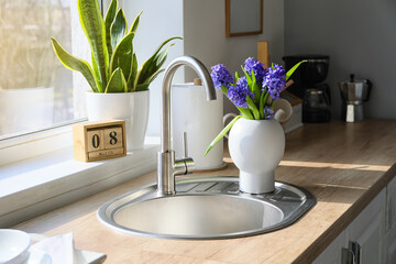 Kitchen counter with sink, beautiful flowers and cube calendar with date 8 MARCH. International Women's Day celebration