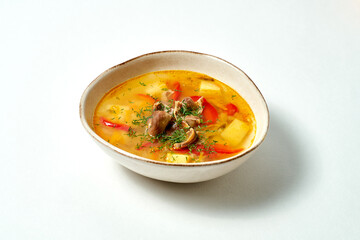 Chicken broth with meat, potatoes and bell peppers on white background