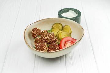 Fried falafel with tomato and cucumber salad on a white wooden background