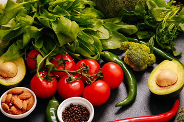 Fresh vegetables closeup. Green leaves of basil, arugula, avocado, tomato branch, chilly peppers, broccoli, almond. Organic food, vegan, vegetarian nutrition, salad cooking, healthy eating concept