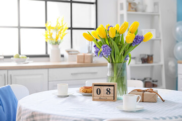 Dining table with cube calendar, flowers, cups and gift box. International Women's Day celebration