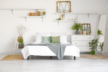 Interior of light bedroom with stepladder, commode and Easter eggs