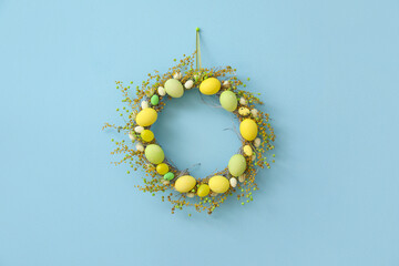 Stylish Easter wreath hanging on blue wall