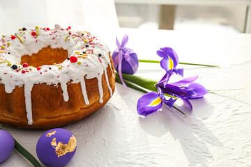 Obraz na płótnie Canvas Tasty Easter cake with eggs and flowers on light background