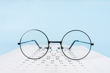 A table for checking vision in Russian, glasses and lenses on a light blue background. a concept for an ophthalmology clinic or the sale of optics