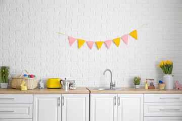 Kitchen counter with different utensils and Easter decor near white brick wall