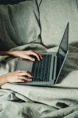hands and laptop on the bed close-up