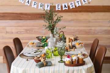 Stylish Easter table setting near wooden wall in room