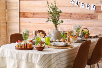 Stylish Easter table setting near wooden wall
